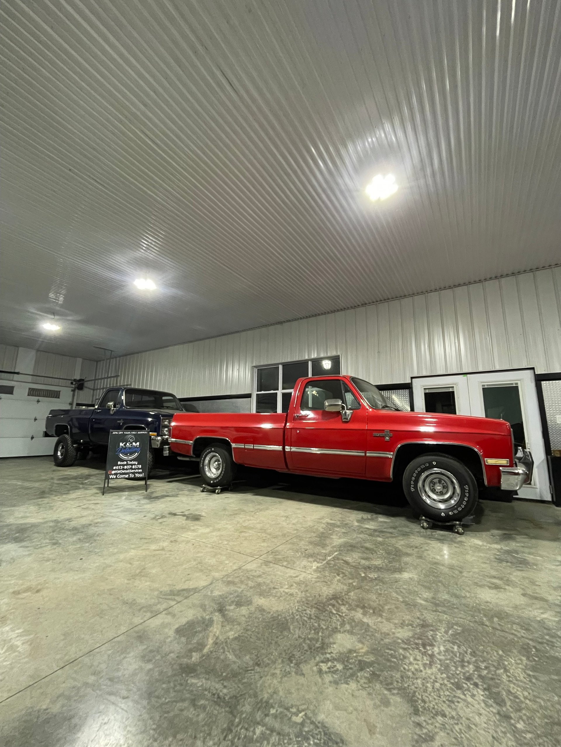 Red pickup truck parked in a modern warehouse with polished concrete floor and metal corrugated ceiling