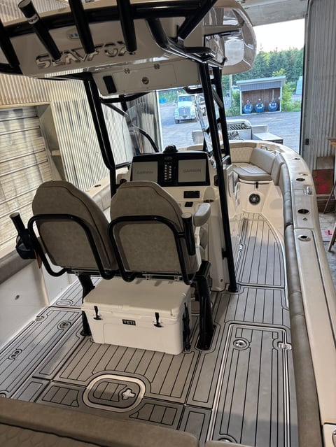 Interior of a center console boat with two front seats, steering wheel, and control panel under the canvas canopy