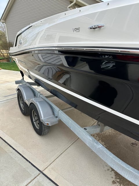 White speedboat on a trailer in a residential driveway next to a house